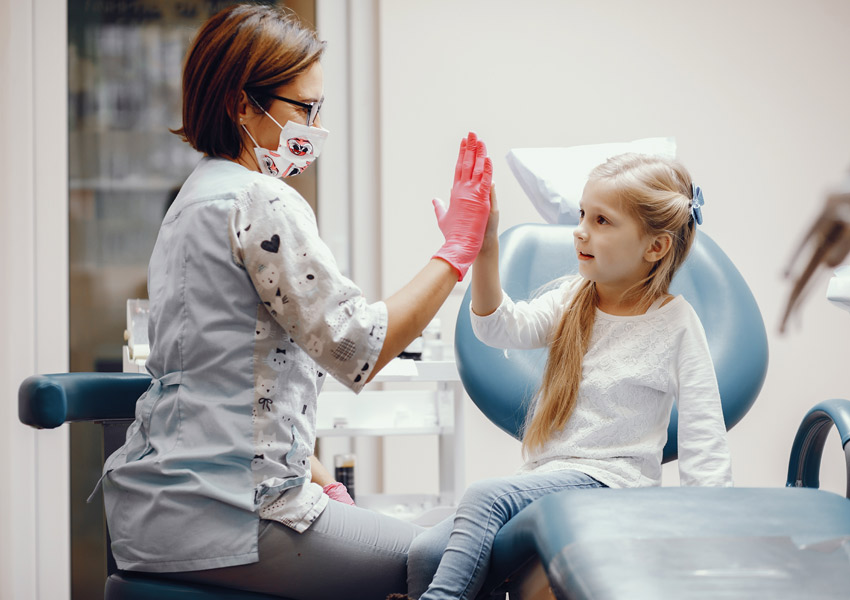Dr. Maria Roman giving high five to young dental patient at Elite Dental Touch
