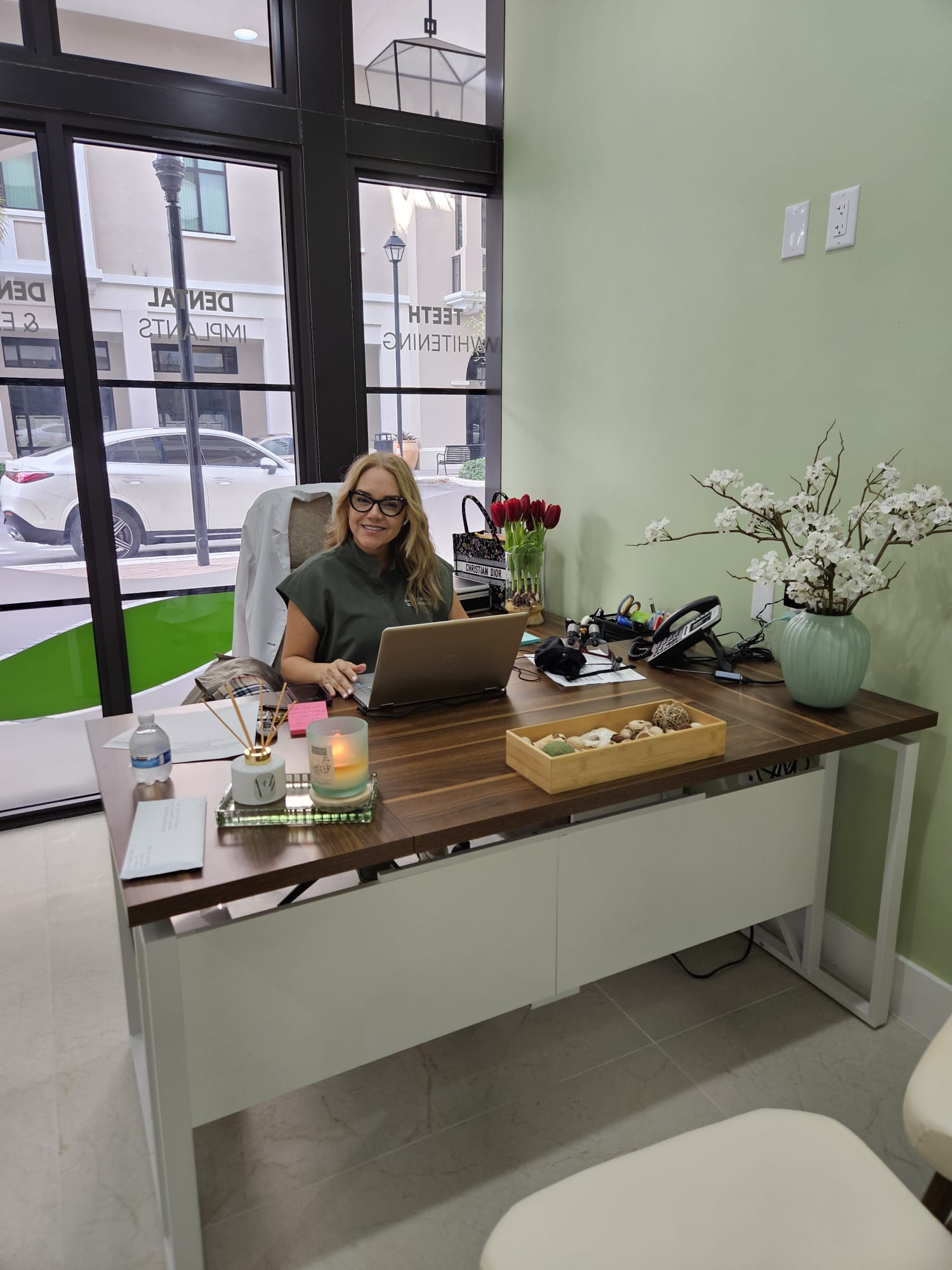 Dr Maria Roman working at desk in Elite Dental office near street windows