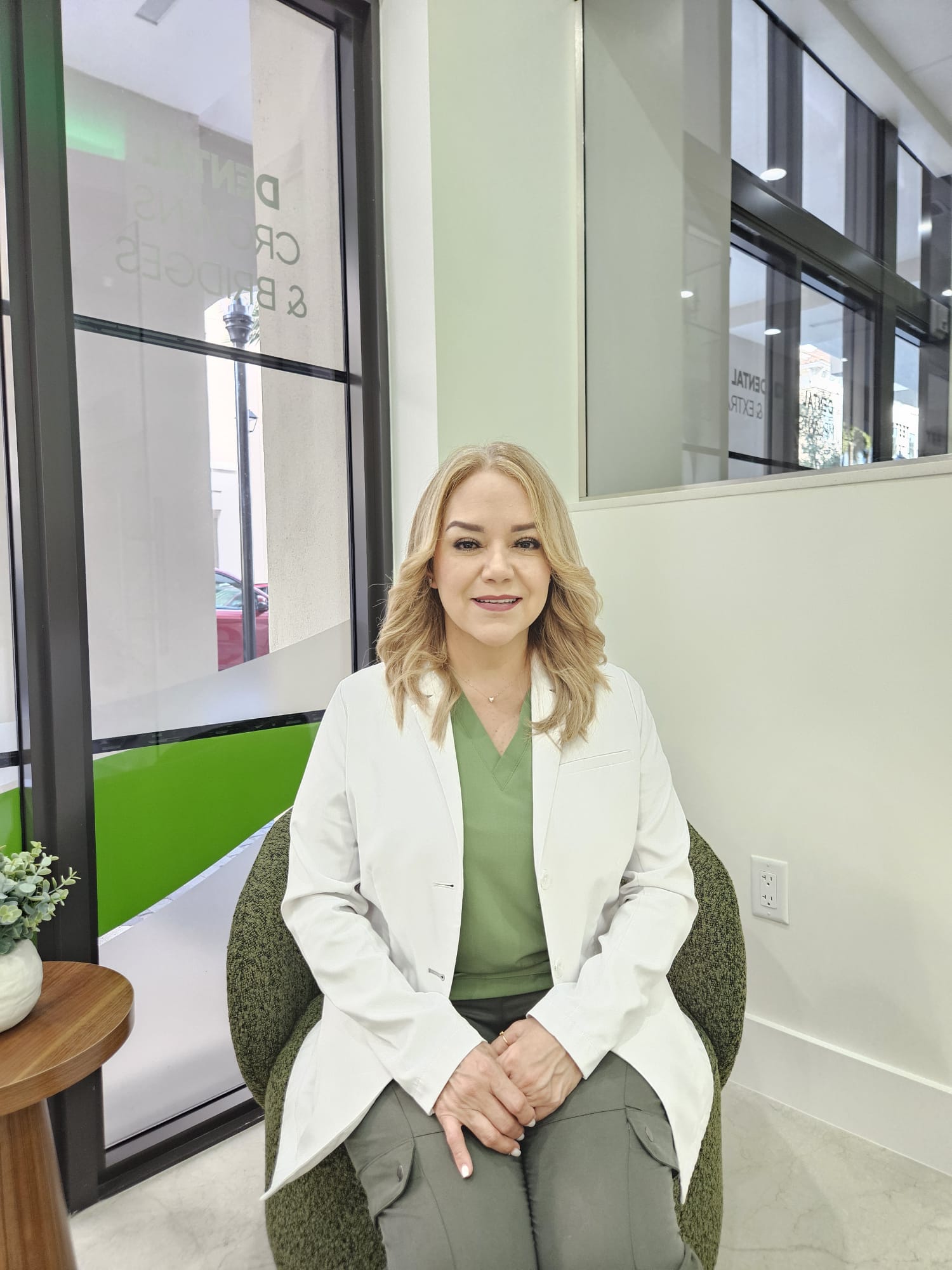 Dr. Maria Roman DDS seated in white coat at Elite Dental Touch office