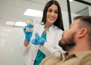 Dental Bridge 2 Female dentist explaining to male patient the benefits of dental implants using a model of a jaw