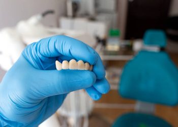 Dental Bridge 7 The dentist holds a ceramic, zirconium, bridge-shaped, non-removable dental prosthesis in his hand. Dental bridge.