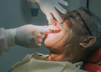 Dental Bridge 4 Dentist inserting denture on patient Asian Chinese senior man 's mouth
