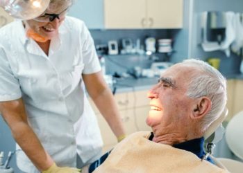 Dental Implants 2 Happy female dentist and an 80's male patient in dentist's office