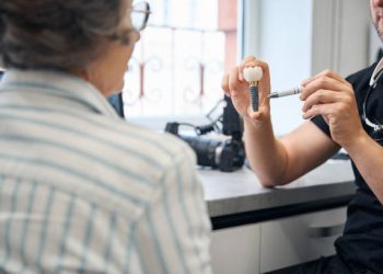 Dental Implants 6 Specialist demonstrates a model of a dental implant to a patient, the dental clinic uses modern technologies