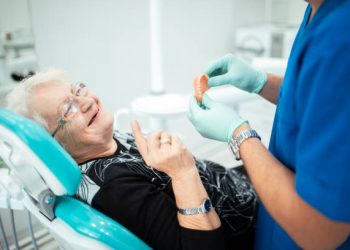 Dentist showing teeth dentures to a patient. Senior woman