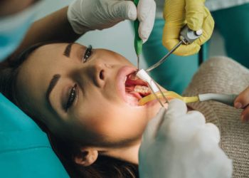 Root Canal 4 Unrecognizable dentist placing cotton swab into woman's mouth during dental procedure.