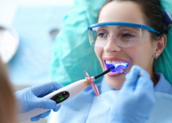 Tooth Bonding 4 Dentist works with dental polymerization lamp in oral cavity. Caries treatment concept