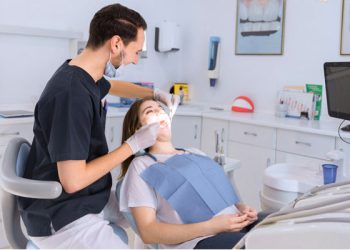 Why Choose Us 2 Dentist performing a dental procedure on a patient at Elite Dental Touch